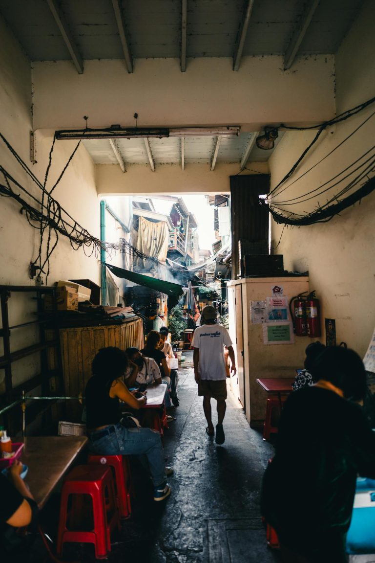 Busy alleyway in Bangkok with people enjoying local street food.