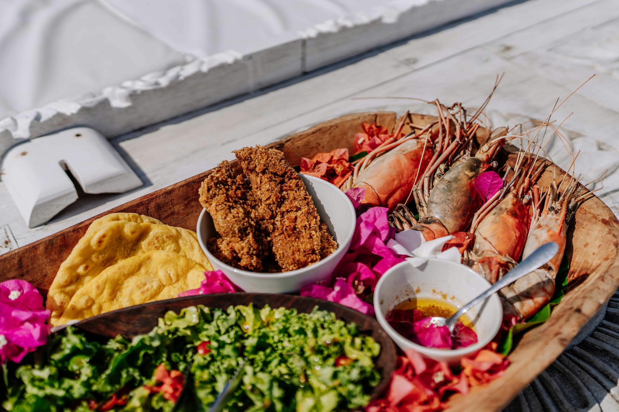 Colorful seafood platter with prawns and salad on a sunny Zanzibar beach.